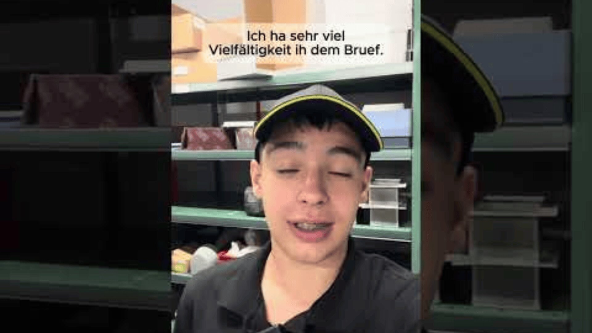 Eine junge Person mit schwarzem Hemd und schwarzer Mütze mit gelber Umrandung steht vor grünen Regalen, die mit Kisten gefüllt sind. Der Text darüber lautet: "Ich ha sehr viel Vielfältigkeit in dem Bruef.