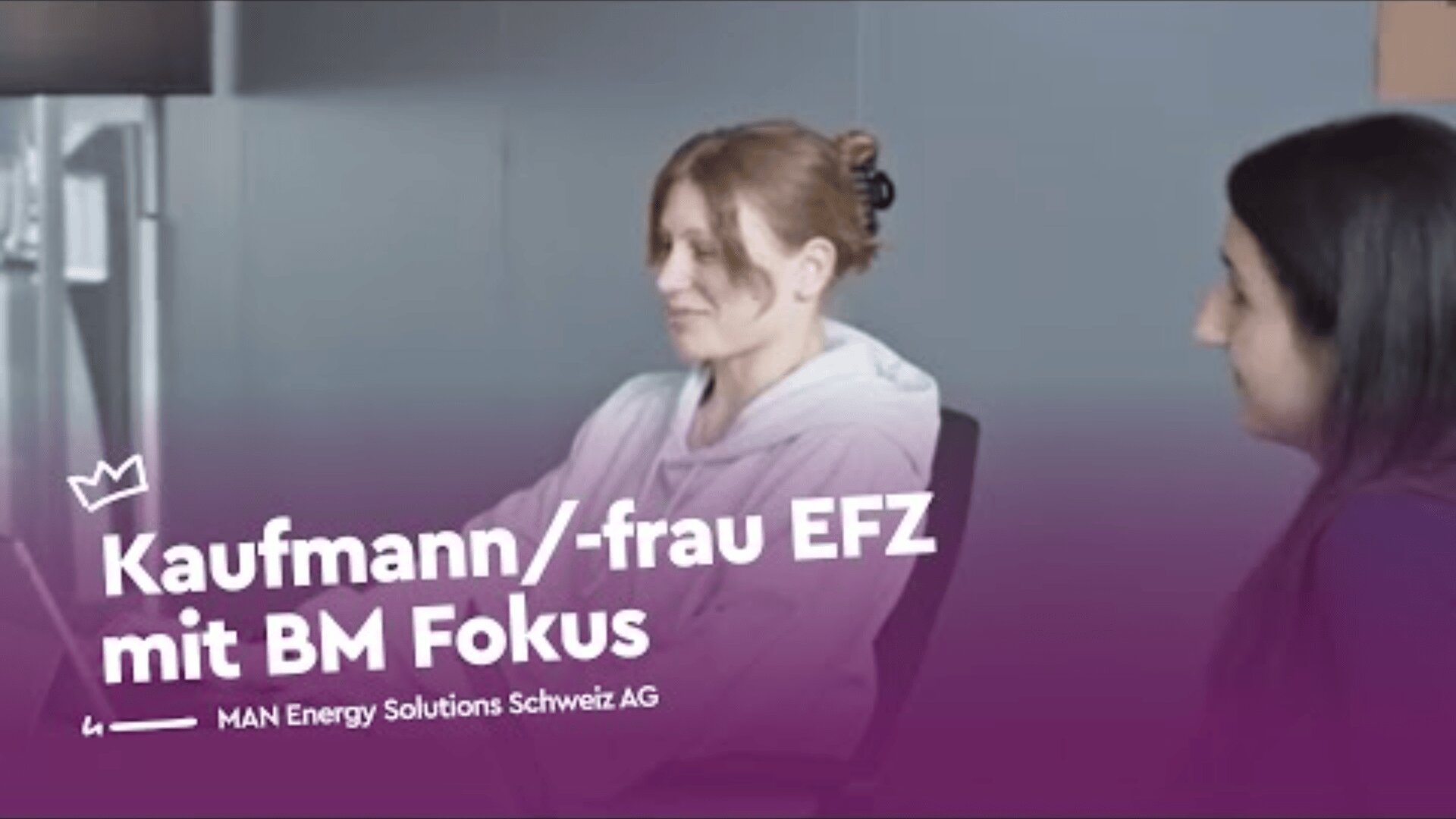 Zwei Frauen sitzen an einem Schreibtisch in einem Büro und schauen auf einen Computerbildschirm. Ein deutscher Text überlagert das Bild und lautet: Kaufmann/-frau EFZ mit BM Fokus und MAN Energy Solutions Schweiz AG.