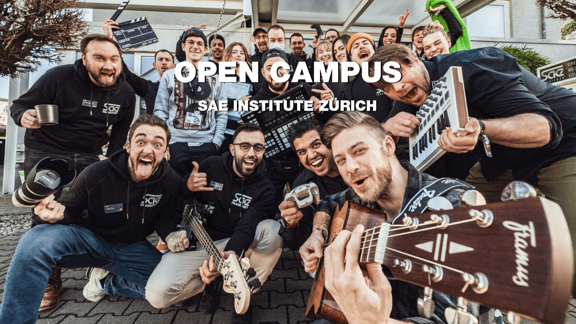 Eine Gruppe aufgeregter junger Erwachsener posiert mit Musikinstrumenten und Ausrüstung vor dem Gebäude des SAE Institute Zürich. Der Text über dem Bild lautet "OPEN CAMPUS SAE INSTITUTE ZÜRICH.".