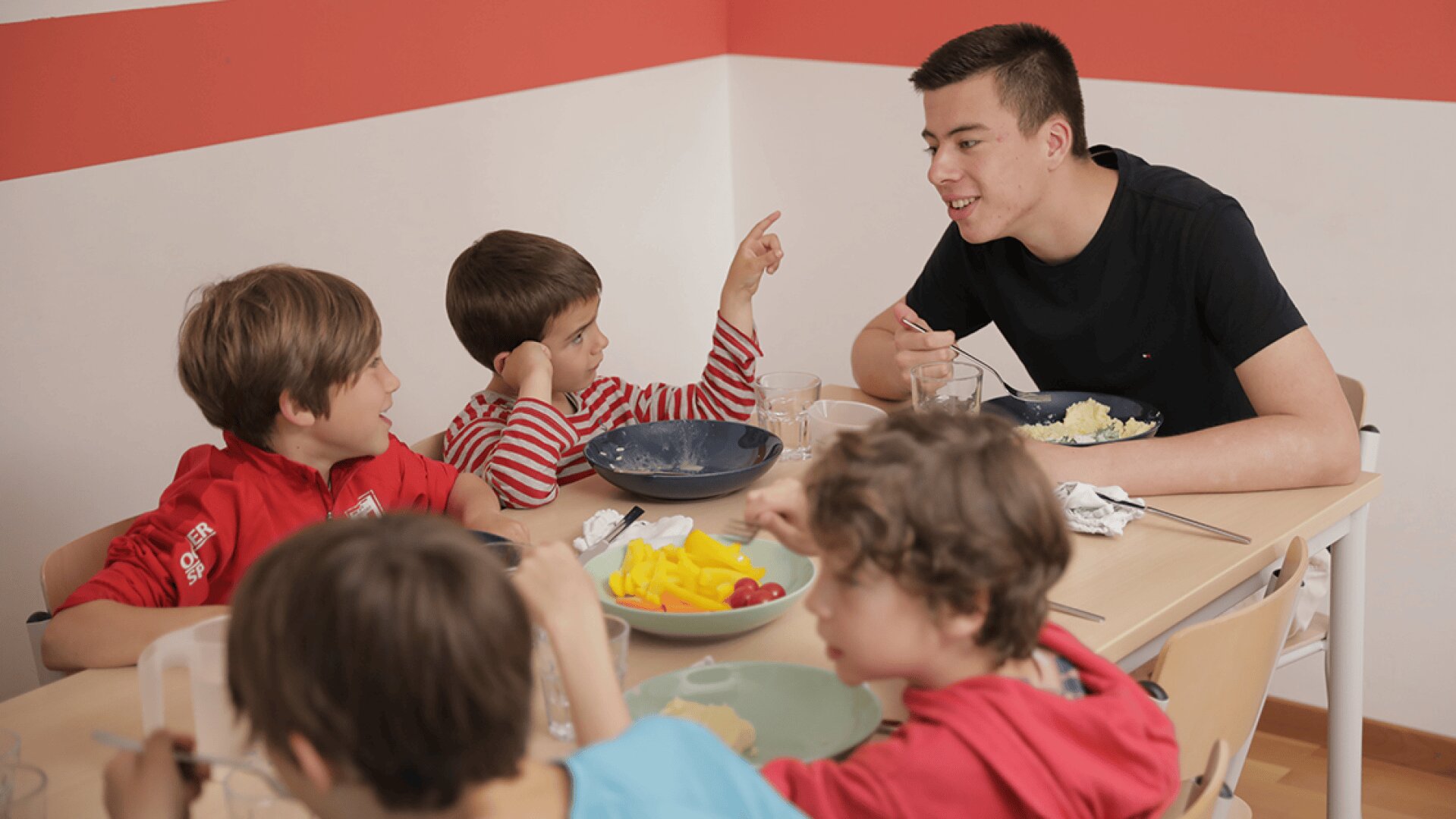 Eine Gruppe von Kindern sitzt um einen Tisch herum und isst.