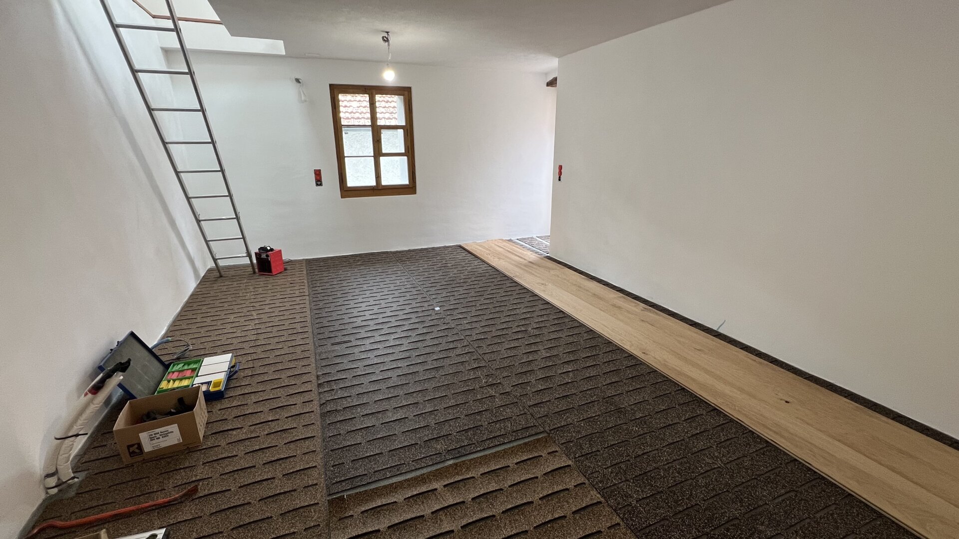 Ein Raum mit einer Leiter und einem Holzboden.