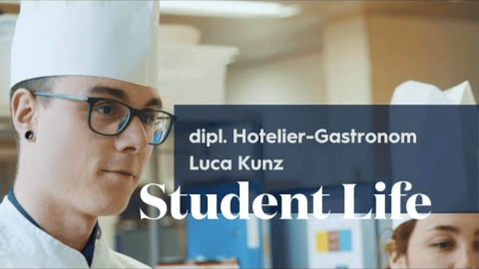 Ein junger Koch in weißer Uniform und Mütze steht in einem Innenraum. Der Text darüber lautet: dipl. Hotelier-Gastronom Luca Kunz Student Life. Eine weitere Person mit Kochmütze ist teilweise im Hintergrund zu sehen.