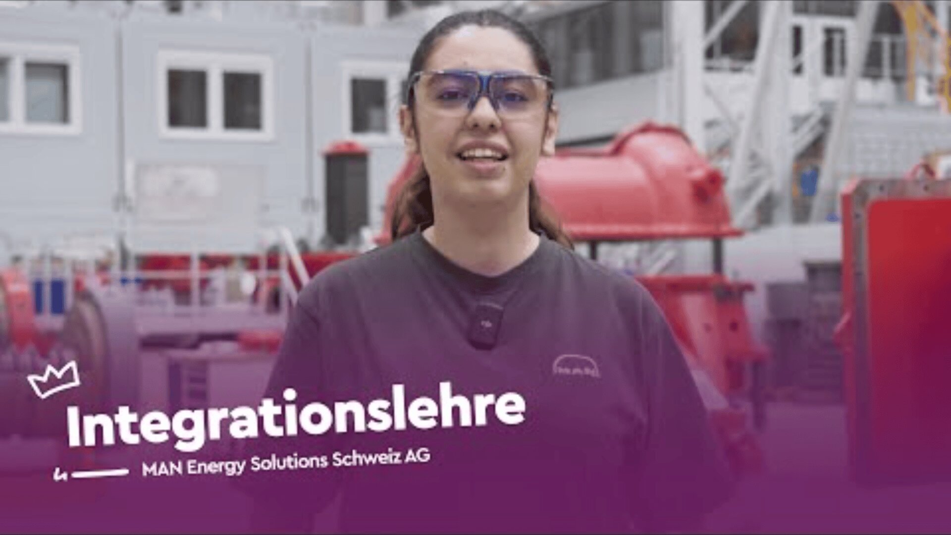 Eine junge Frau mit Schutzbrille und Mikrofon lächelt in einer Industrieumgebung. Der Text Integrationslehre und MAN Energy Solutions Schweiz AG ist unten auf einem violetten Overlay zu sehen.