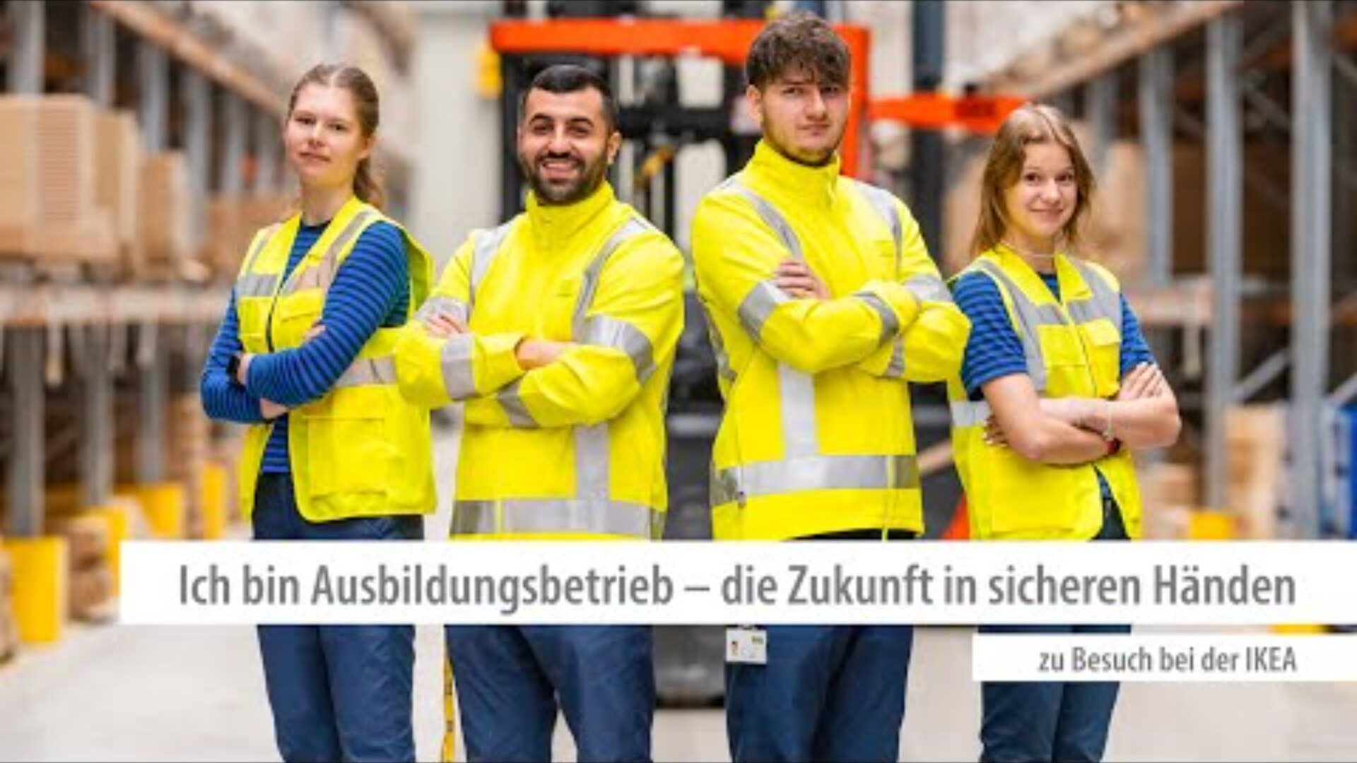 Vier junge Erwachsene in gelben Sicherheitswesten stehen selbstbewusst mit verschränkten Armen in einer Lagerhalle. Der Text lautet auf Deutsch: Ich bin Ausbildungsbetrieb - die Zukunft in sicheren Händen. Zu Besuch bei der IKEA.