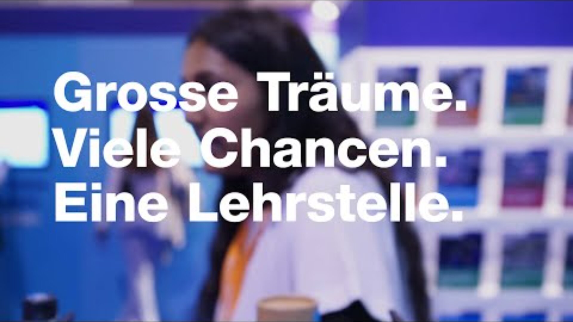 Eine Person steht vor einem blauen und violetten Hintergrund, auf dem ein deutscher Text eingeblendet ist: Grosse Träume. Viele Chancen. Eine Lehrstelle. (Große Träume. Viele Chancen. Eine Lehrstelle.).