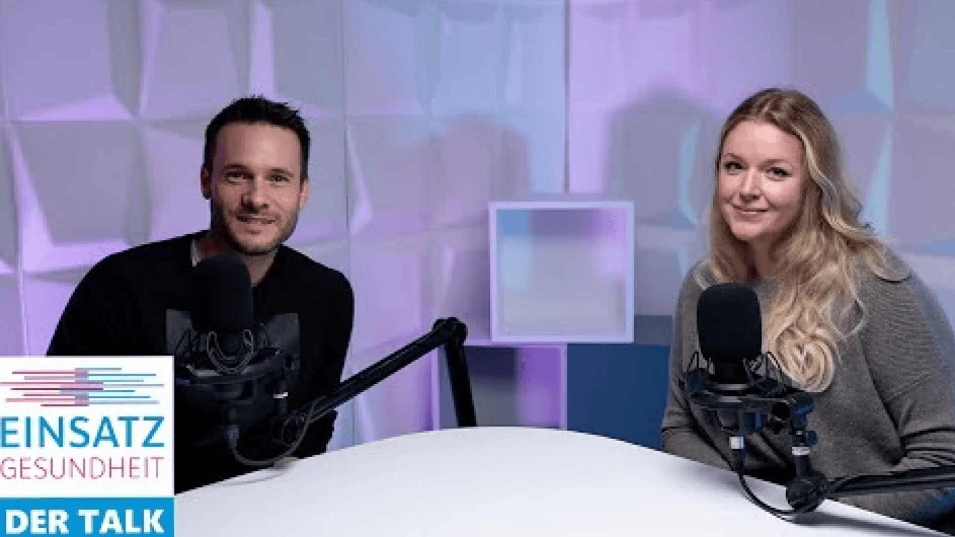 Ein Mann und eine Frau sitzen an einem Tisch mit Mikrofonen und lächeln in die Kamera in einem modernen Studio mit lila Beleuchtung. In der Ecke steht ein Logo mit der Aufschrift EINSATZ GESUNDHEIT DER TALK.