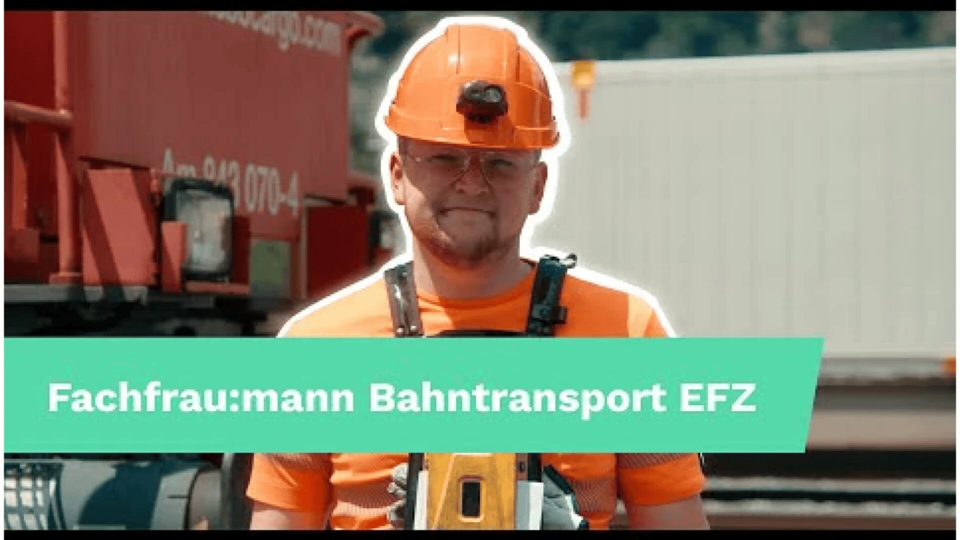 Ein Eisenbahner mit orangefarbenem Schutzhelm und Sicherheitsweste steht vor einem roten Zug. Auf einem grünen Banner quer über dem Bild steht: Fachfrau:mann Bahntransport EFZ.